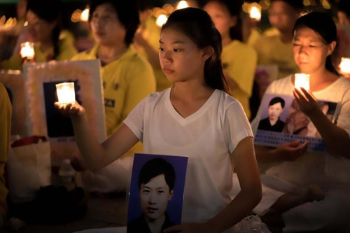 V SPOMIN IZGUBLJENIH: Mlado dekle drži fotografijo Falun Gong praktikanta, ki je bil mučen in ubit na Kitajskem.