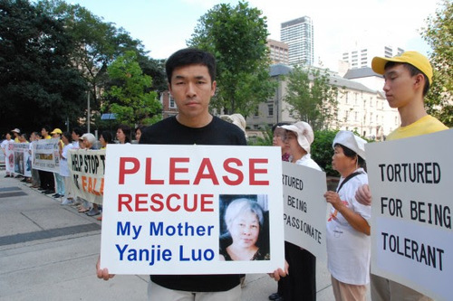VZTRAJNA IN MIROLJUBNA PRITOŽBA: Pred veleposlaništvom Kitajske ima g. Wenta Fan napis poleg slike svoje mati Yanjie Luo, ki je bila leta 2011 obsojena na 13 let zapora na Kitajskem zaradi vadbe Falun Gonga.