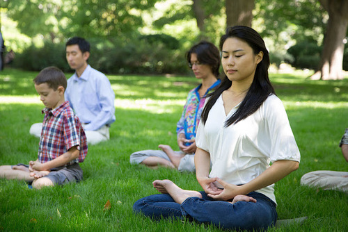Falun Dafa praktikanti v parku izvajajo meditacijo.
